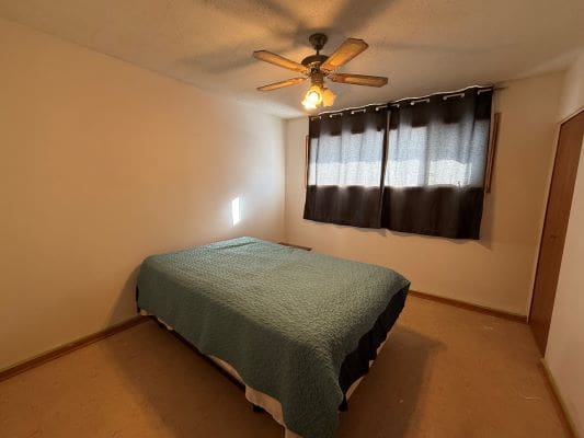 Simple bedroom with bed and ceiling fan.