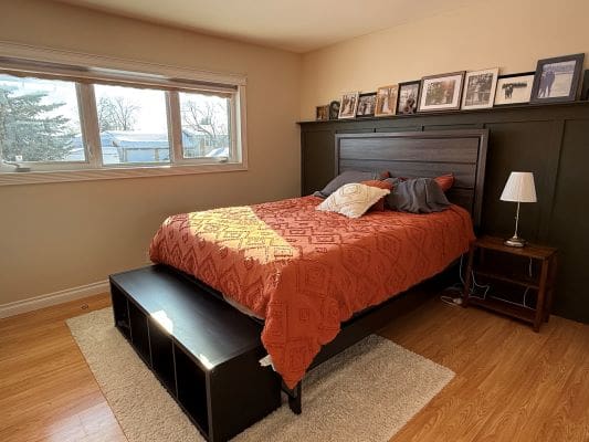 Bedroom with bed, photos, and window view.