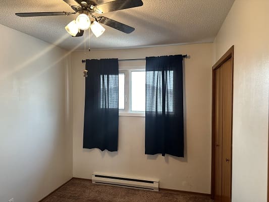 Empty room with window and ceiling fan.