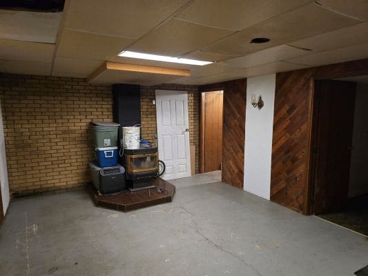 Basement with wood stove and brick wall.