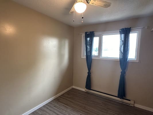 Empty room with window and blue curtains.
