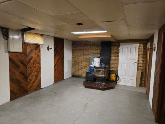 Basement room with wood paneling and stove.