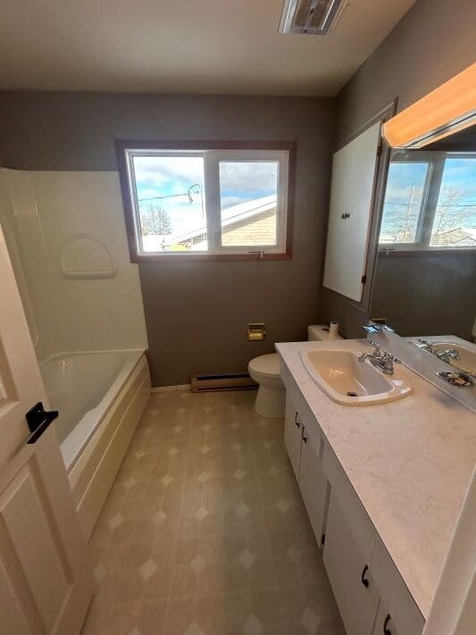 Bathroom with tub, sink, and window view.
