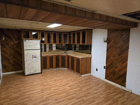 Wood-paneled kitchen with fridge and cabinets.