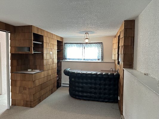 Retro basement bar with wood paneling.