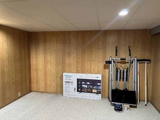 Basement with exercise equipment and TV box.