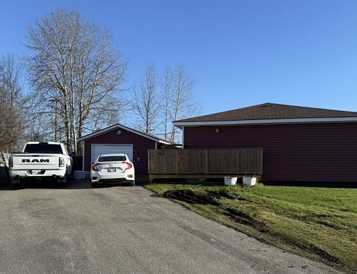 Driveway with parked cars and red house.