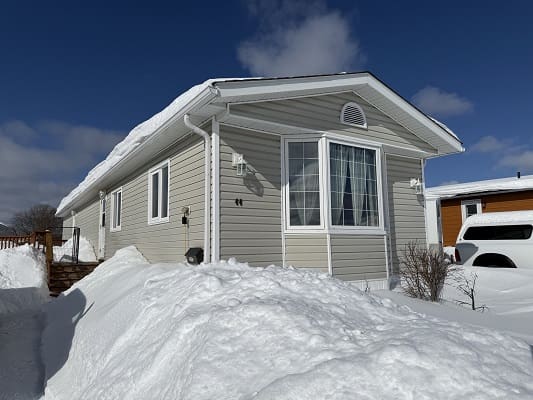 Snow-covered house under clear blue sky.