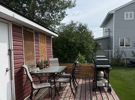 Backyard patio with chairs and barbecue grill.