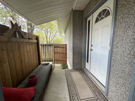 Covered porch with bench and white door.