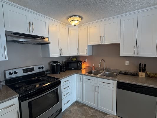 Modern kitchen with white cabinets and appliances.