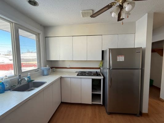 Simple kitchen with white cabinets and fridge.