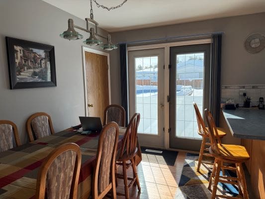 Dining room with table, chairs, and sunlight.