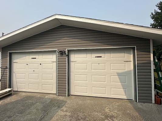Two closed white garage doors, grey exterior.
