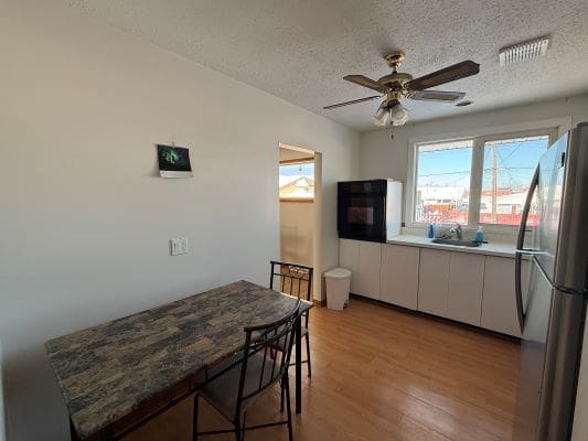 Simple kitchen with table and ceiling fan.