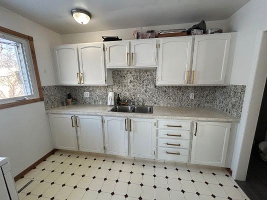 White kitchen cabinets with tiled backsplash.