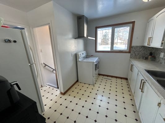 Small kitchen with white cabinets and stove.