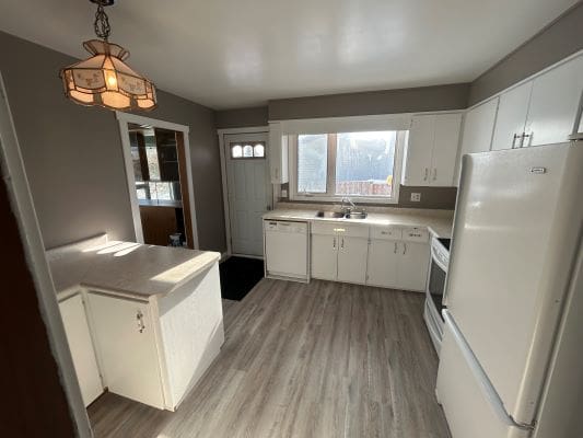 Modern kitchen with white cabinets and appliances.