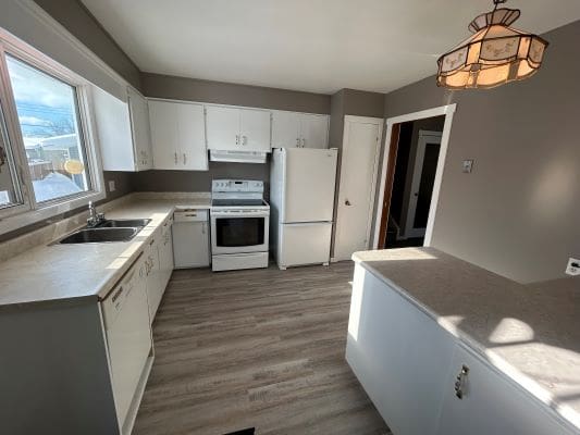 Modern kitchen with white cabinets and appliances.