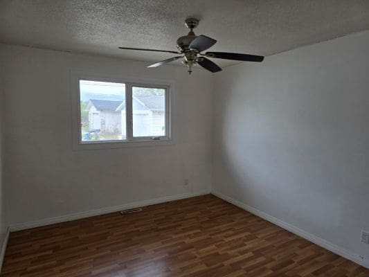 Empty room with window and ceiling fan.