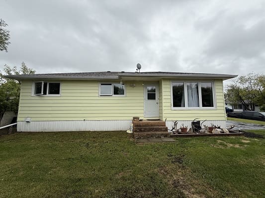 Single-story yellow house with cloudy sky.