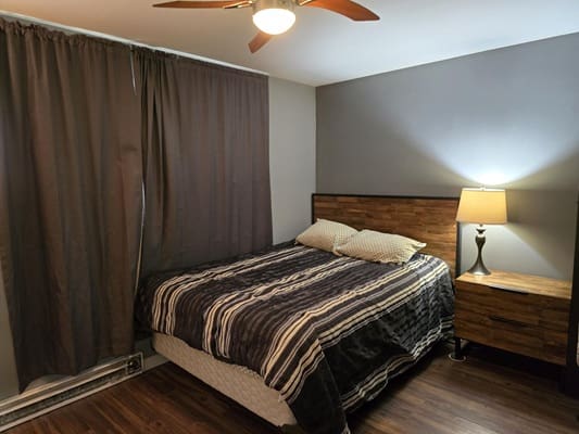 Cozy bedroom with striped bedding and lamp.