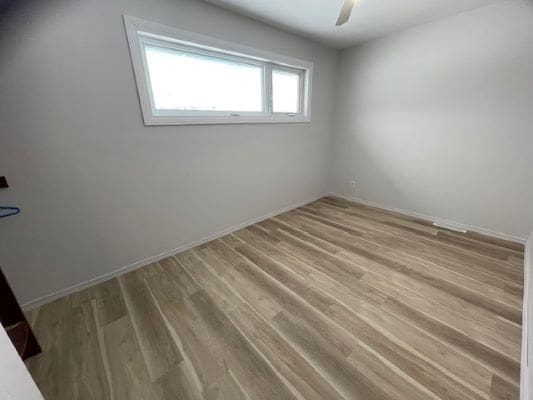 Empty room with wooden flooring and window.