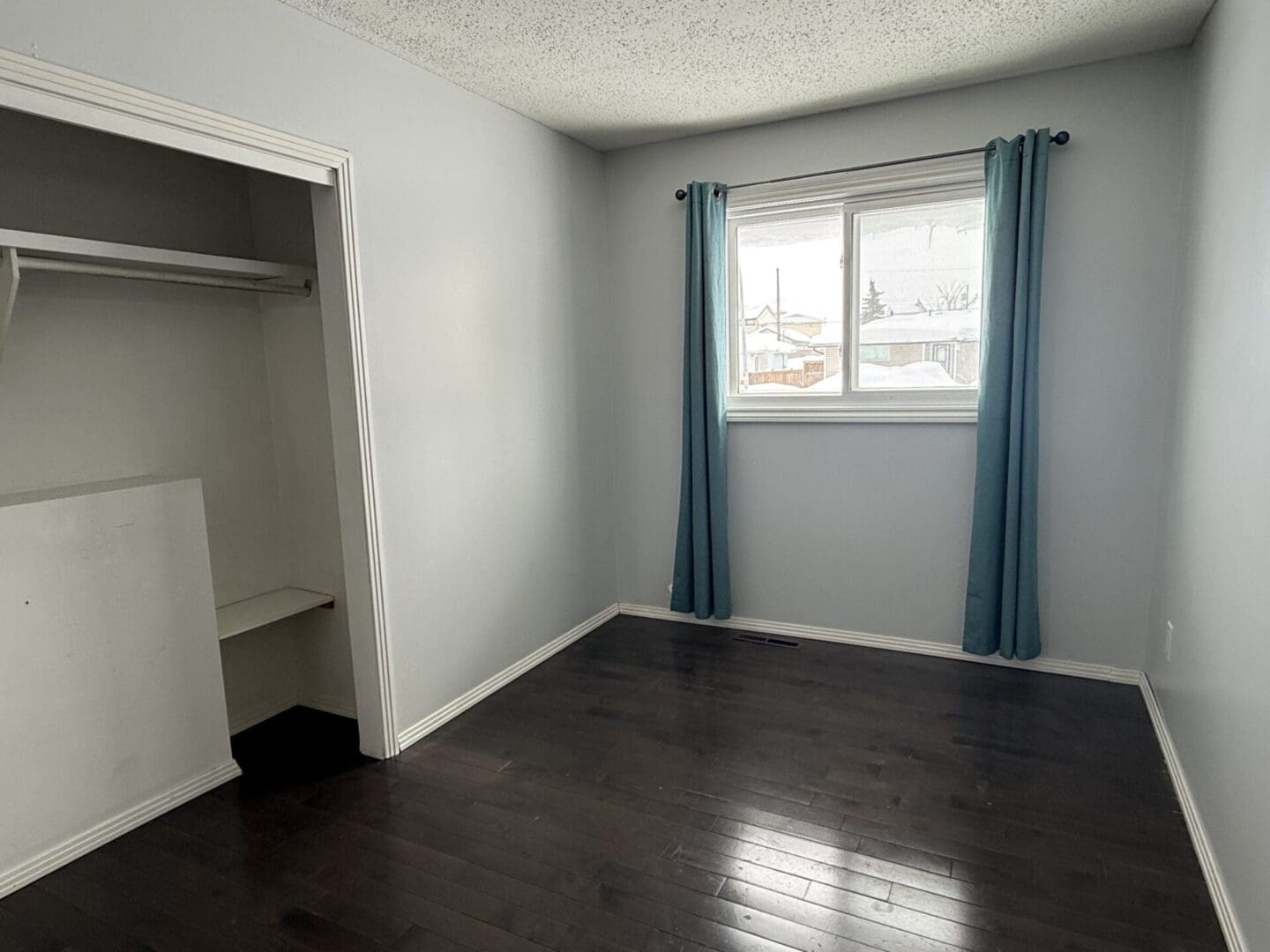 Empty room with closet and window curtains.