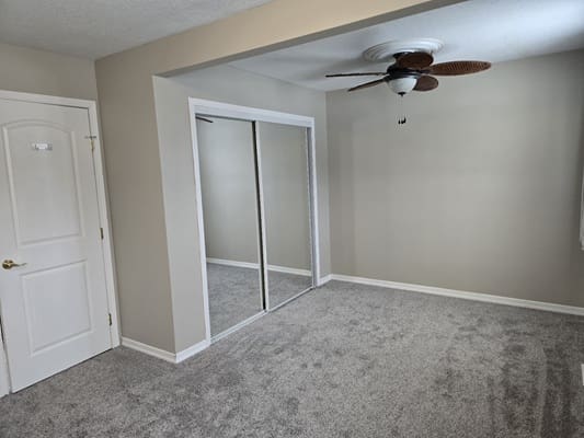 Empty room with carpet and ceiling fan.