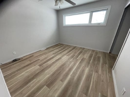 Empty room with wooden flooring and window.
