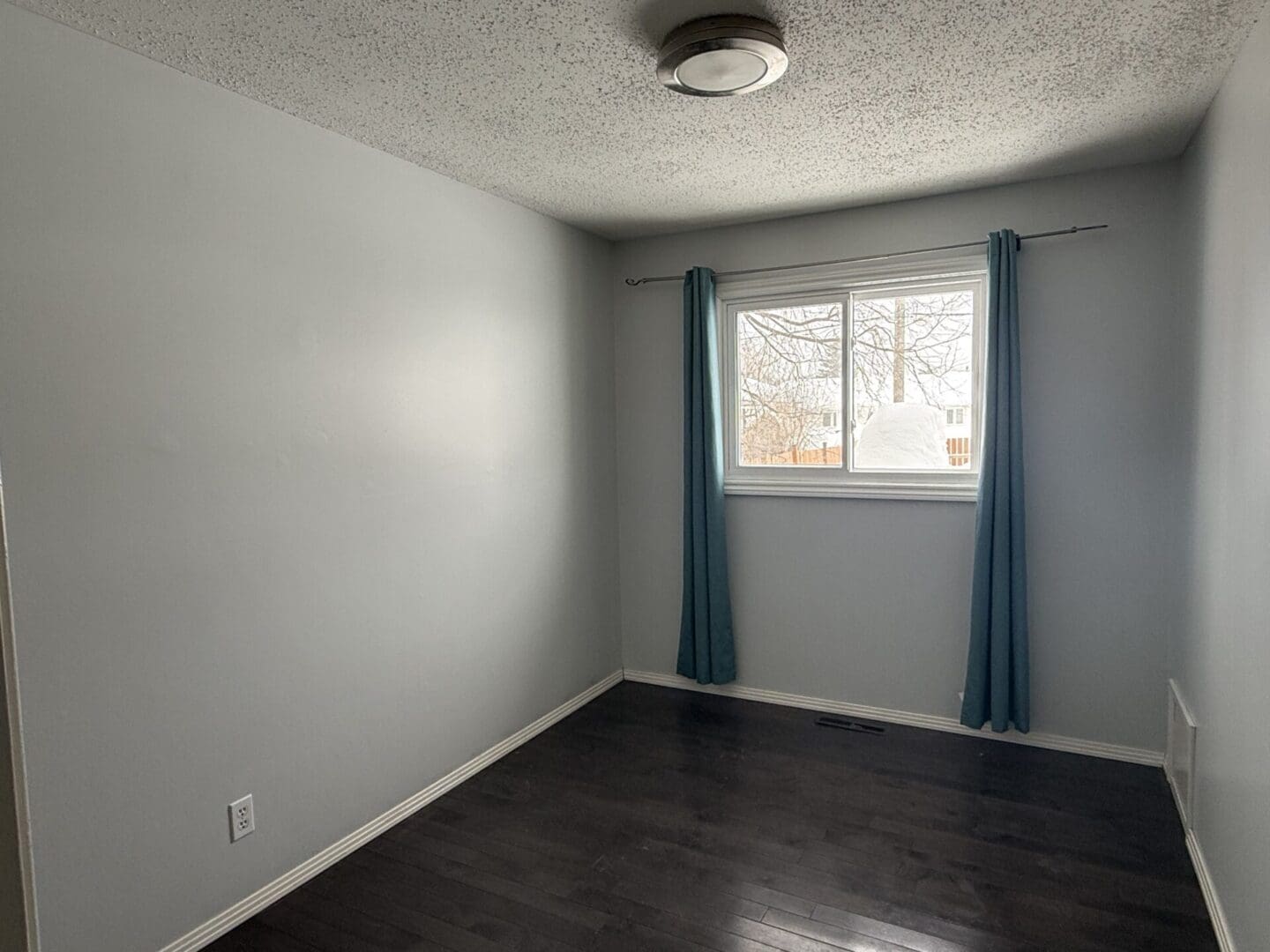 Empty room with window and blue curtains.