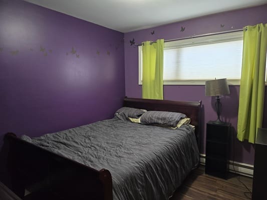 Bedroom with purple walls and gray bedding.