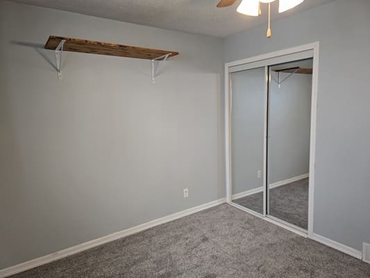 Empty room with shelf and mirrored closet.