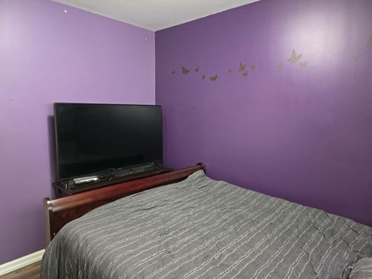 Purple bedroom with bed and wall decals.