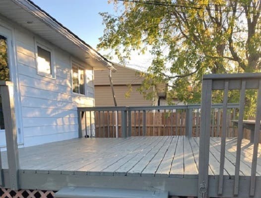 Wooden deck attached to house, sunny day.