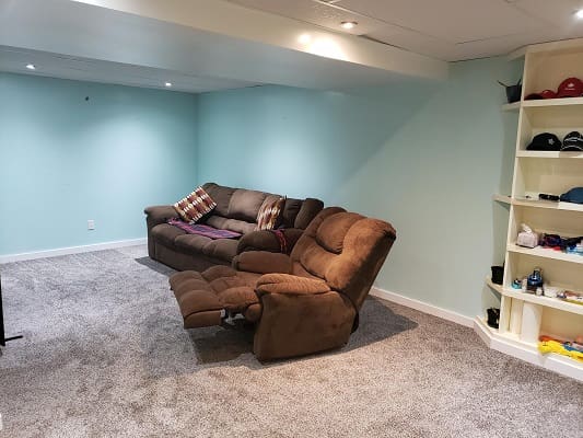 Basement with brown sofa and light blue walls.