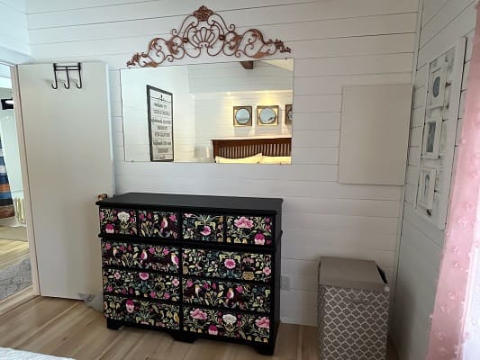 Floral dresser with mirror in bedroom.