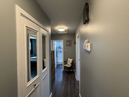 Narrow hallway with wooden floor and chair.