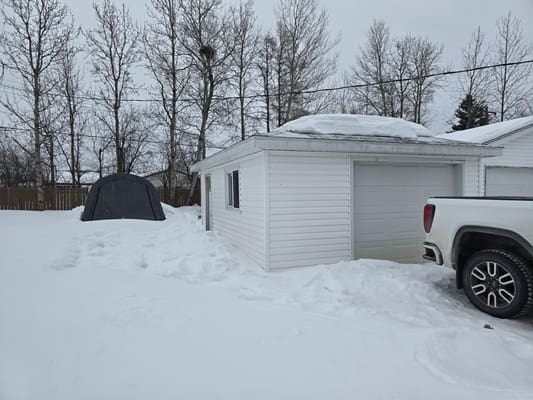 Snow-covered garage and truck in winter.