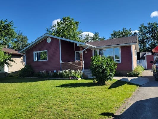 Red house with lawn under clear sky.
