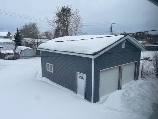 Blue garage covered in winter snow.