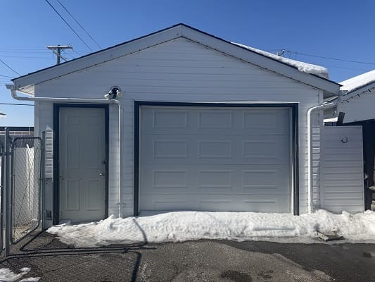White garage with snow on the ground.
