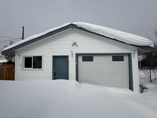Snow-covered garage with blue door.