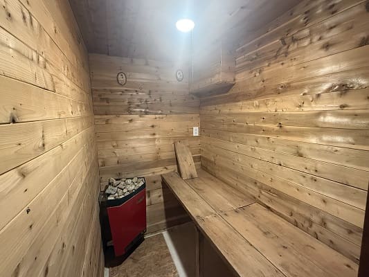 Wooden sauna room with heater and bench.