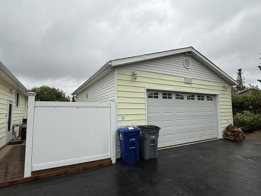 Yellow garage with recycling bins outside.
