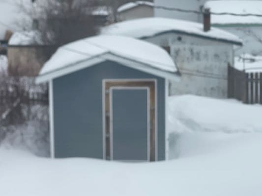 Snow-covered shed in a winter landscape.