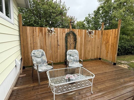 Patio with chairs and wooden privacy fence.