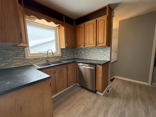Small kitchen with wooden cabinets and dishwasher.