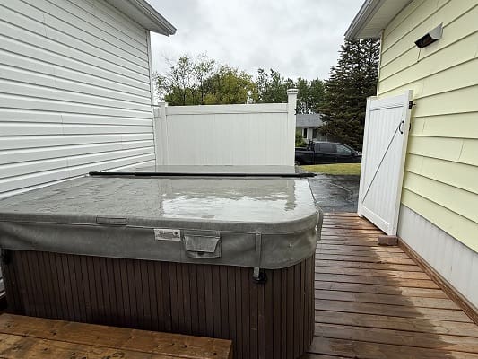 Covered hot tub on wooden deck outdoors.