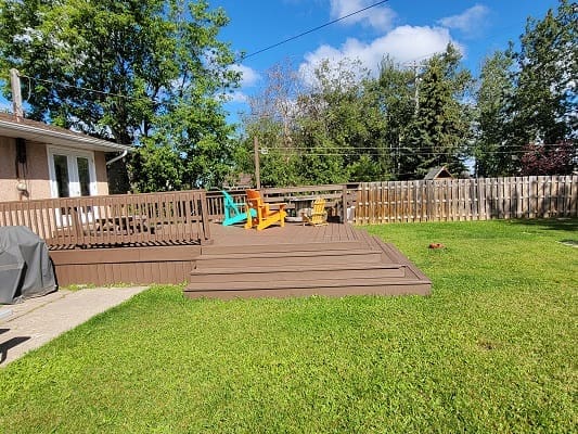 Wooden deck with colorful chairs and grass.